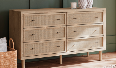 Wooden dresser with wicker accents against a green wall